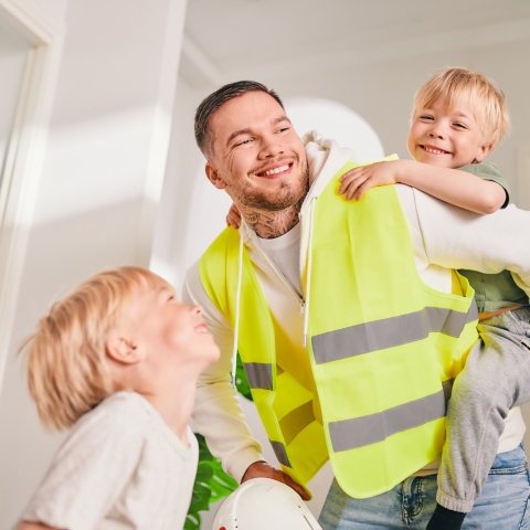 Töistä palannut isä iloitsee lasten kanssa.