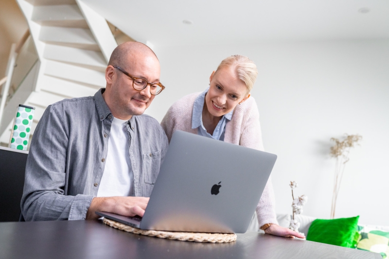 Pariskunta täyttää lainahakemusta tietokoneella.